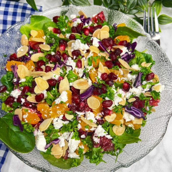 dark leafy green salad with oranges, pomegranates, feta cheese and sliced toasted almonds
