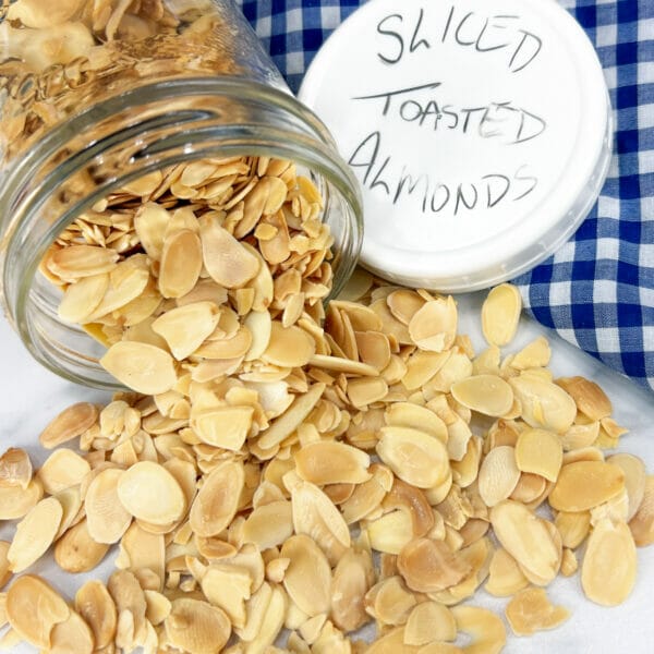 toasted sliced almonds spilling out of jar with labeled lid
