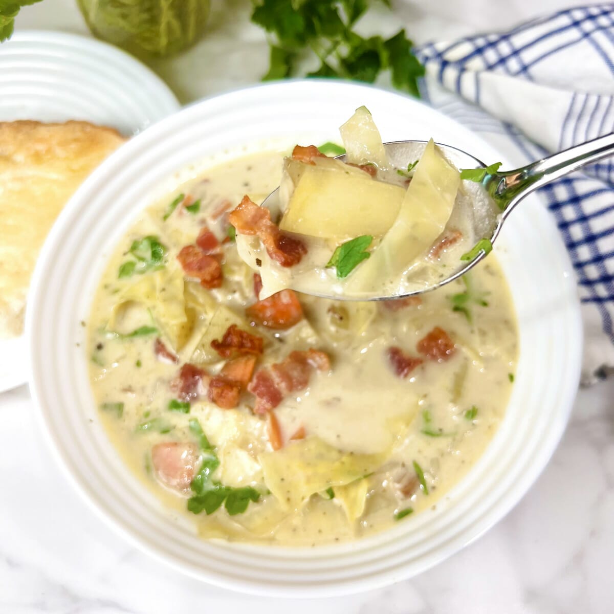 creamy cabbage soup in bowl with spoon garnished with bacon