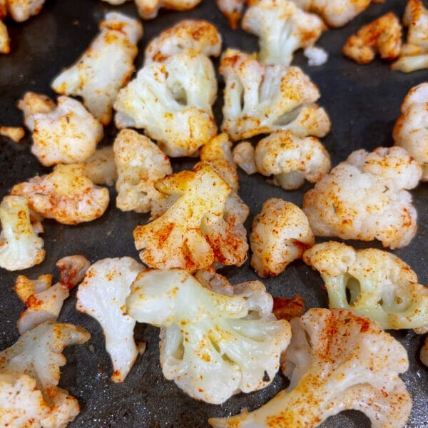 Cauliflower pieces with seasoning showing little browning.

