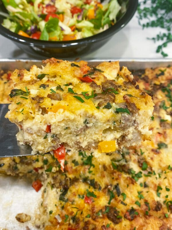 sausage breakfast strata with egg texture showing while on scoop over tray
