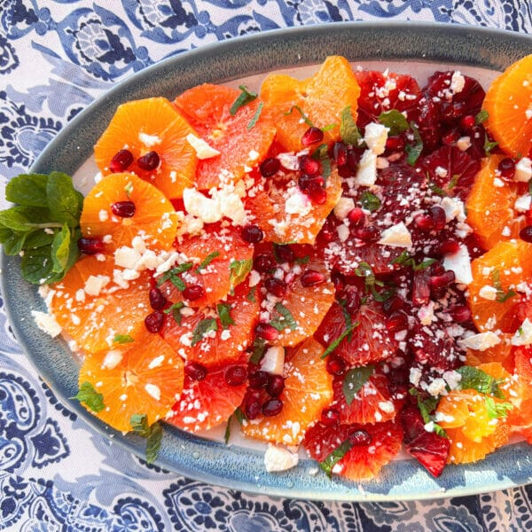 different variety of orange slices on platter with feta, mint and pomegranates