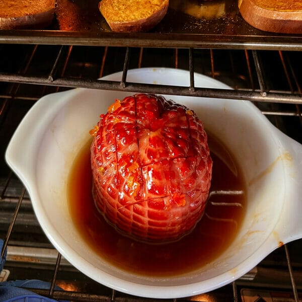 half a fully cooked ham in a dish in oven with glaze