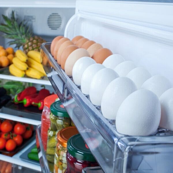 white and brown eggs in the door of a full refrigerator