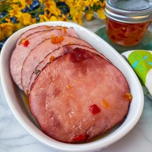 fully cooked ham slices on a small platter with hot pepper jelly glaze