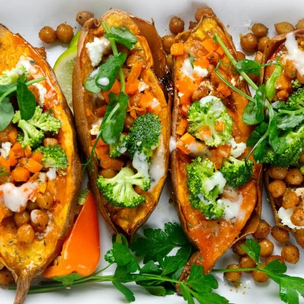 sweet potatoes topped with veggies, dressing and herbs