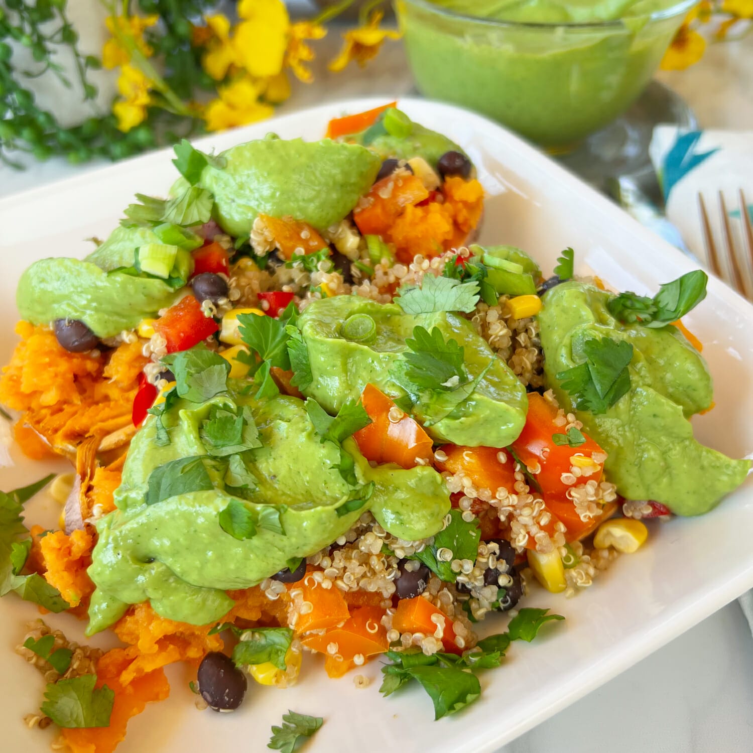 sweet potatoes with quinoa, black beans and sweet peppers topped with fresh avocado sauce