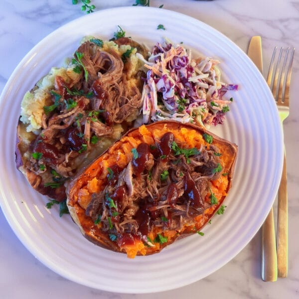 two colors of sweet potatoes stuffed with pulled pork on plate with cole slaw