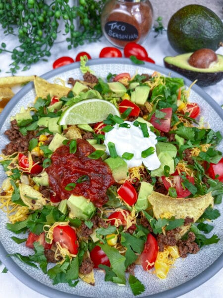 taco salad before tossing in bowl with tomatoes on side