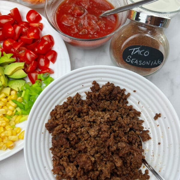 taco salad toppings with close up of taco meat and seasoning in jar