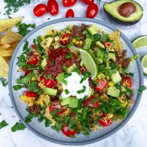 taco salad in bowl with avocado and tomatoes on side
