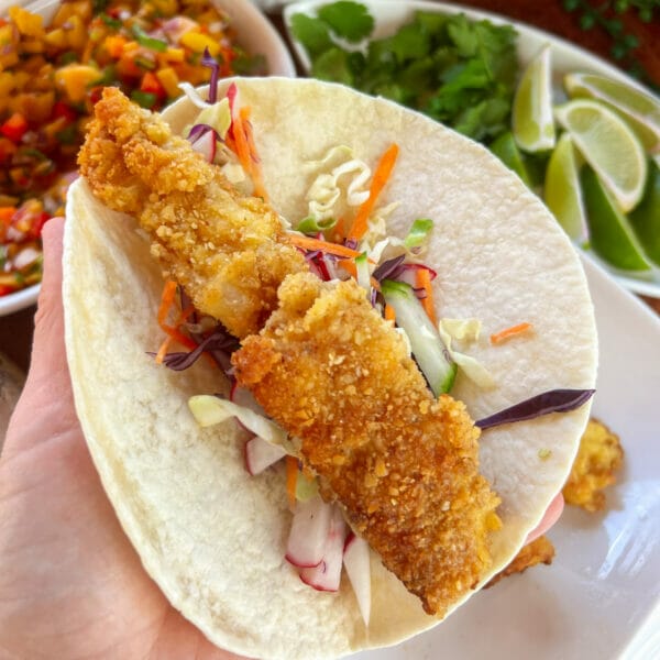 crispy battered fish on coleslaw in small tortilla
