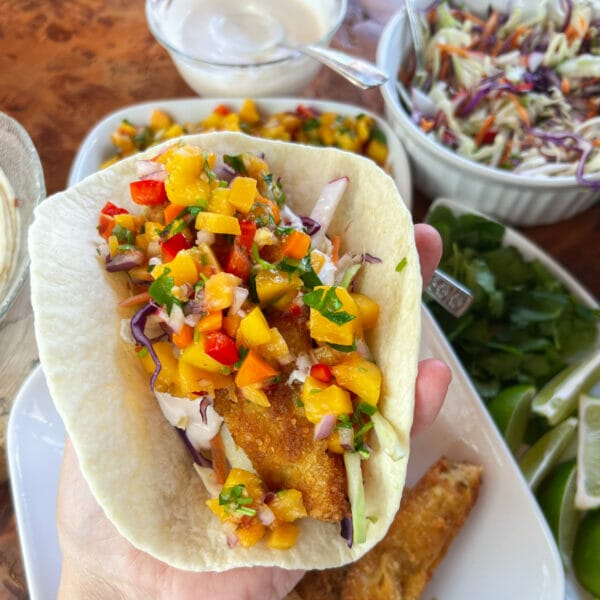 loading up a fish taco with coleslaw, fish and fruit salsa