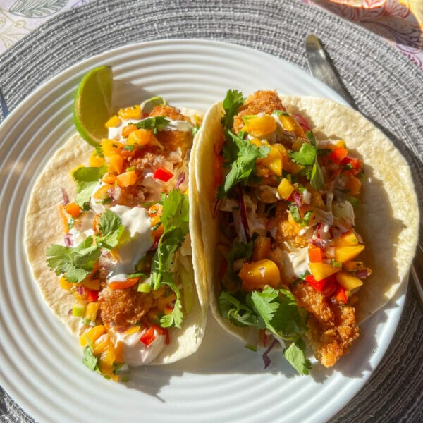 two fully loaded fish tacos on plate ready to eat
