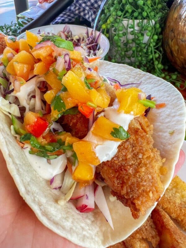 close up of fully loaded crispy battered homemade fish taco in hand