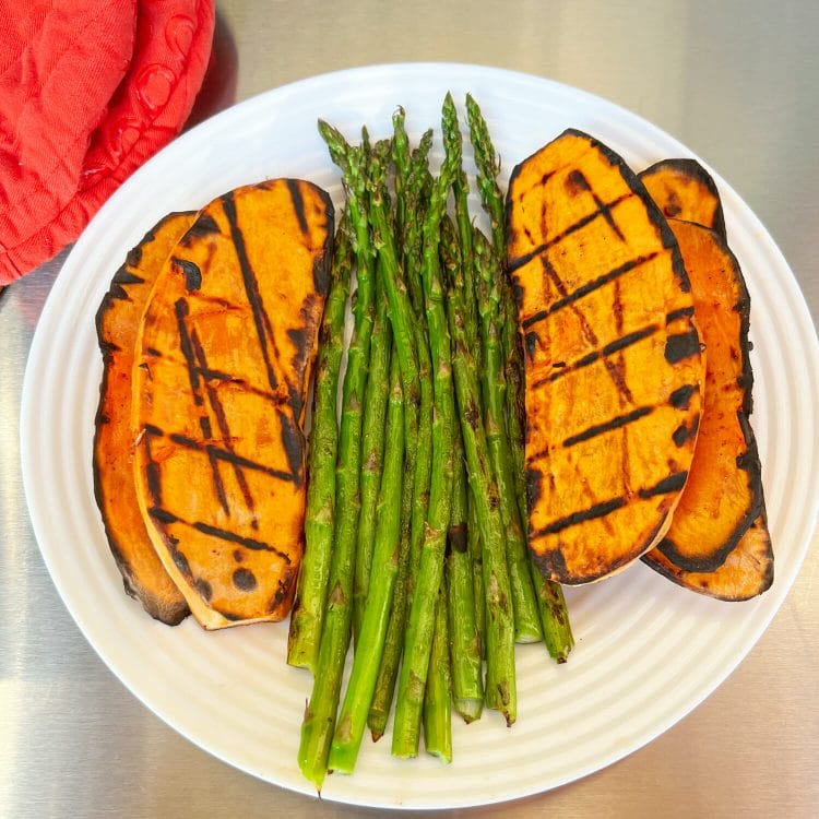grilled sweet potato sliced lengthwise with grilled asparagus on plate