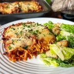 close up of baked spaghetti on plate with salad