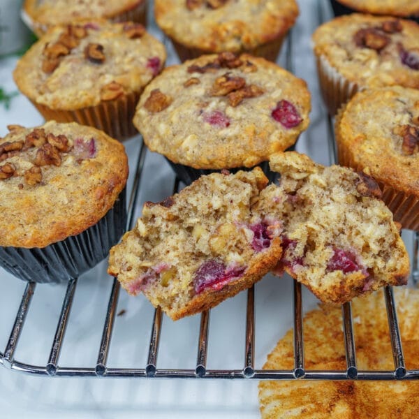 cranberry oat muffins, with one cracked open to show nuts and berries inside