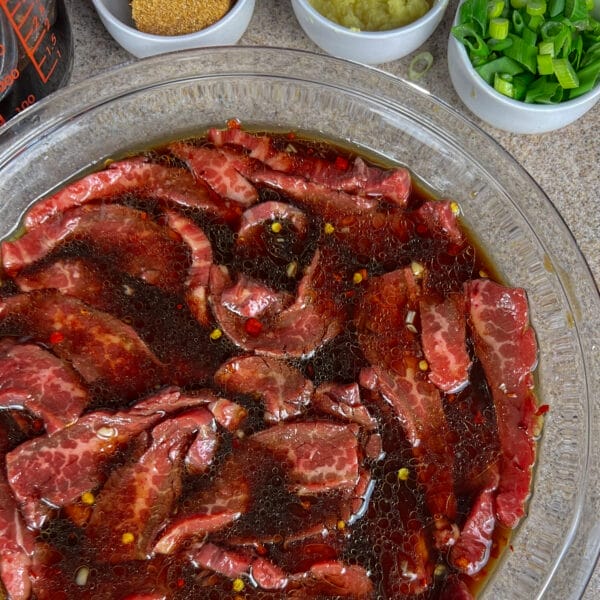 beef strips marinating in shallow glass pie dish