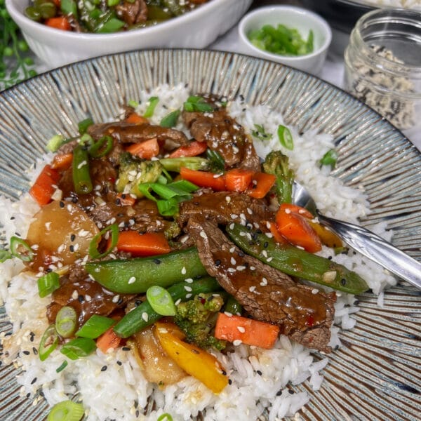 beef and vegetable stir fry on rice on plate