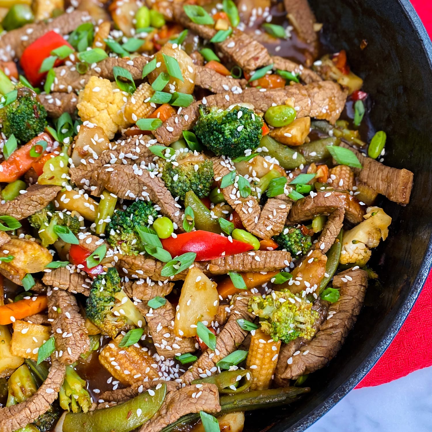 beef and vegetable stir fry with sesame seeds in pan
