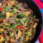 beef and vegetable stir fry with sesame seeds in pan