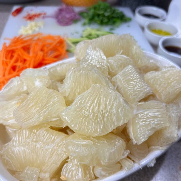 pomelo pieces in a dish with carrots in background
