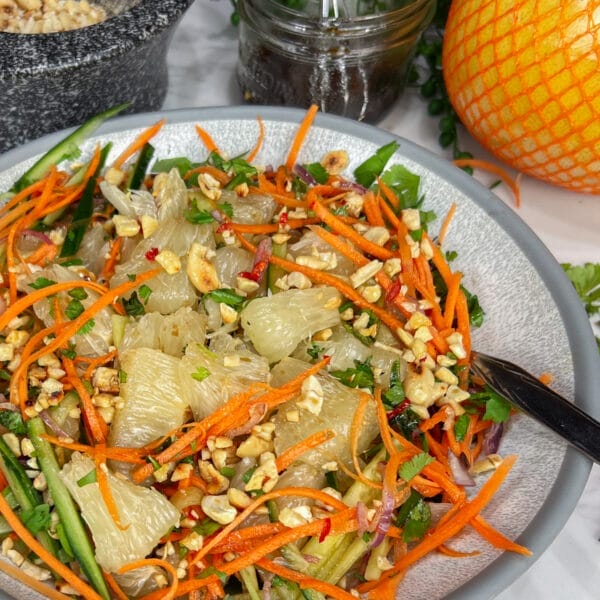 pomelo salad in bowl showing pomelo pieces, carrots, nuts and cucumbers