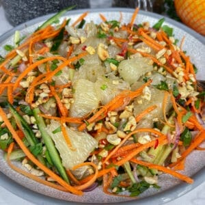 pomelo salad in bowl with pomelo, carrots , nuts and cucumbers prominent