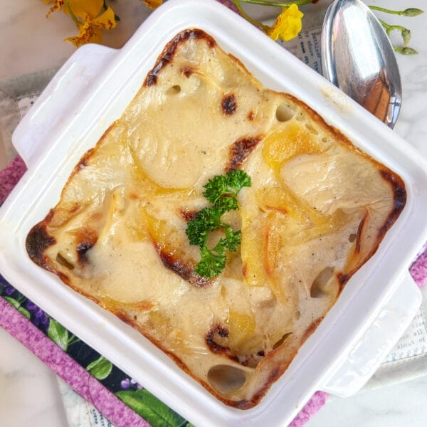 cooked scalloped potatoes in small casserole with sprig of parsley