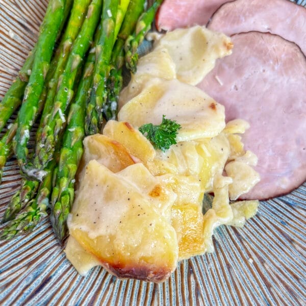 scalloped potatoes on plate with ham and asparagus