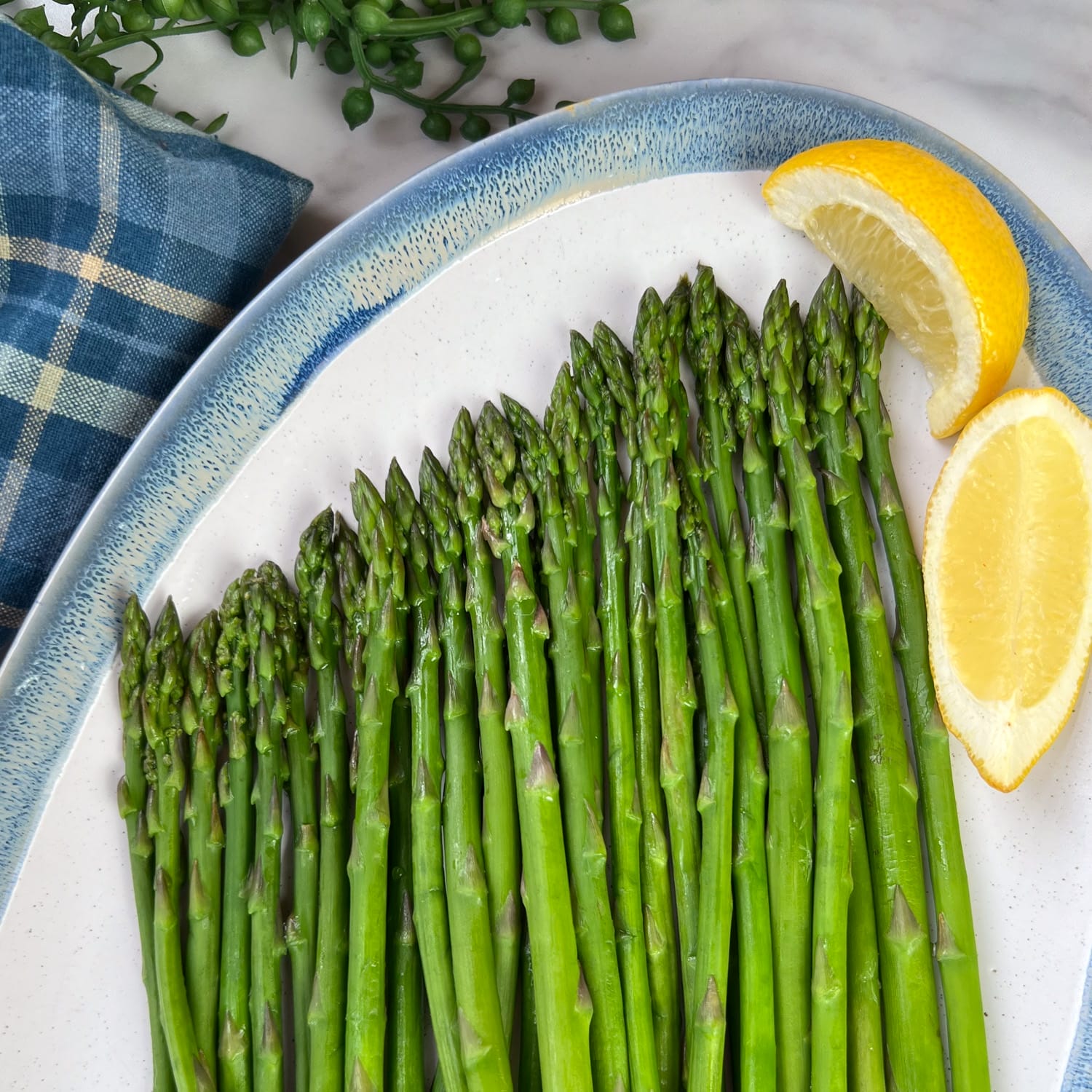 steamed asparagus on platter with lemon wedges