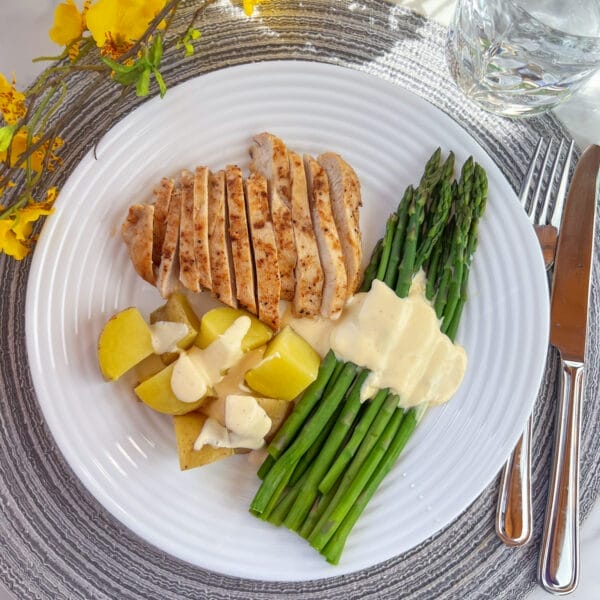 white dinner plate with asparagus chicken potatoes and hollandaise sauce