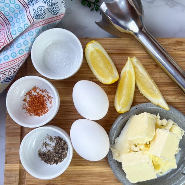 eggs blender lemon wedges and seasonig on cutting board