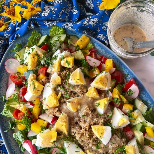 egg and quinoa on salad with vinaigrette on side