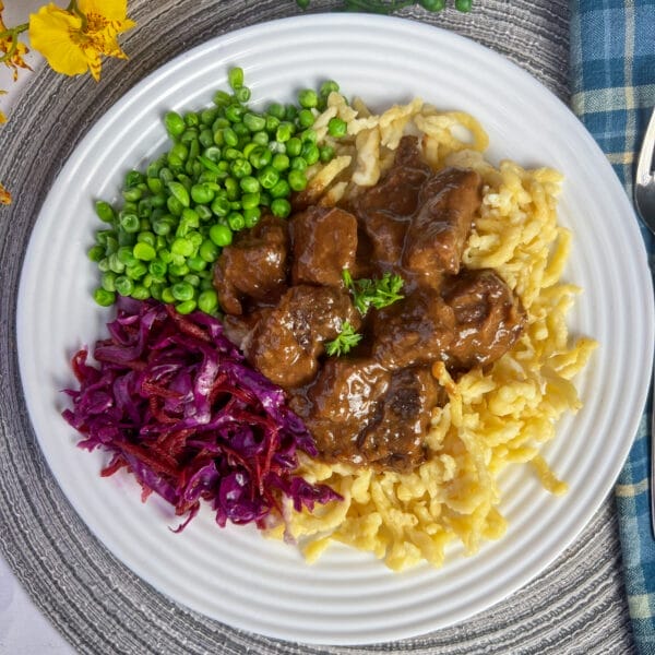 plate with noodles goulash red cabbage and peas